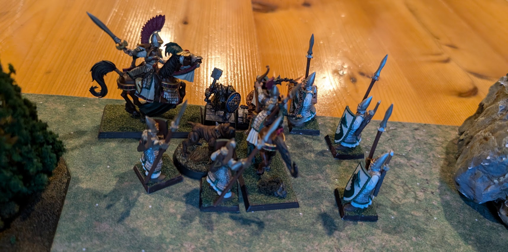 Elven spearmen and mounted warriors surround a dwarf and a dog near the edge of the battlefield.